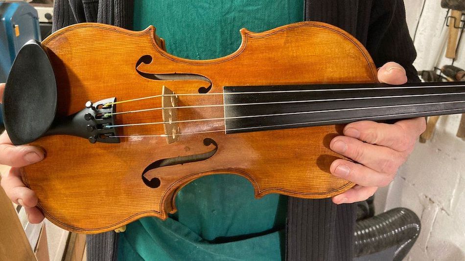 Luthier holding violin made from vegan materials