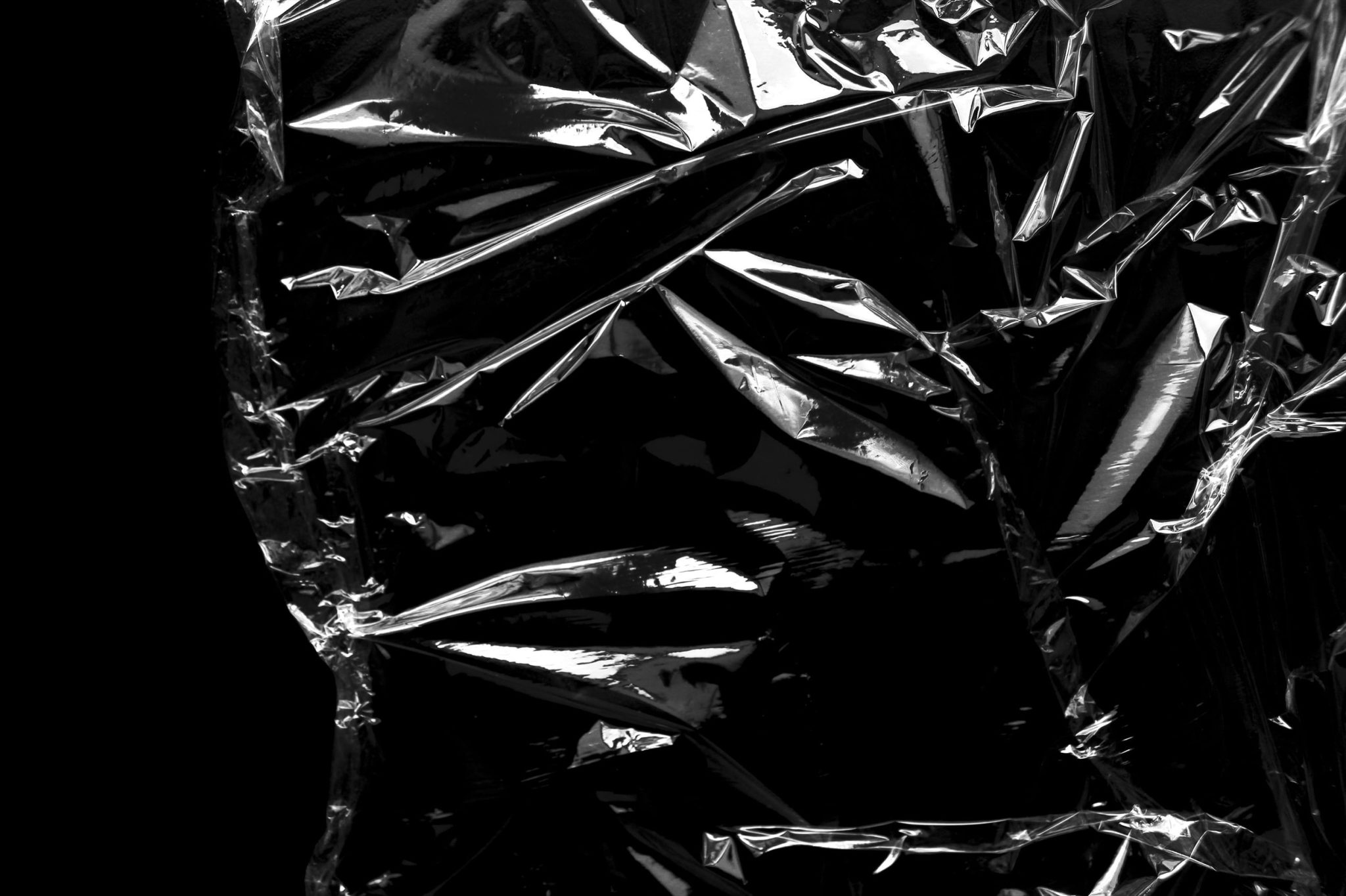 Close-up of shiny crumpled aluminum foil against a black background.