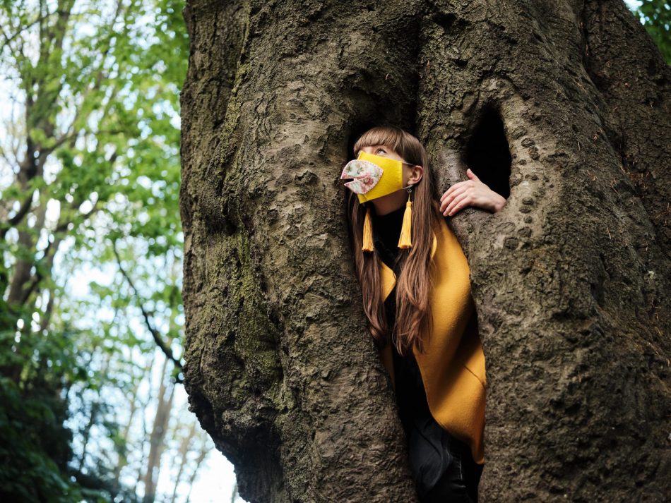 young climate activist in hand-made canary costume poses in tree for climate change