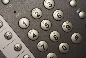 Close-up of a keypad with round gray number keys labeled with letters (2–9) and adjacent function keys visible on a textured surface