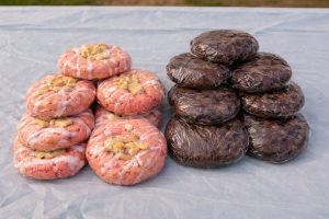 808440255_2213555272834387_4933938149556729751_n | The Optimist Daily: Making Solutions the News Two stacked piles of donuts on a plastic sheet: pink glazed donuts with crumb topping on the left and dark chocolate glazed donuts on the right.