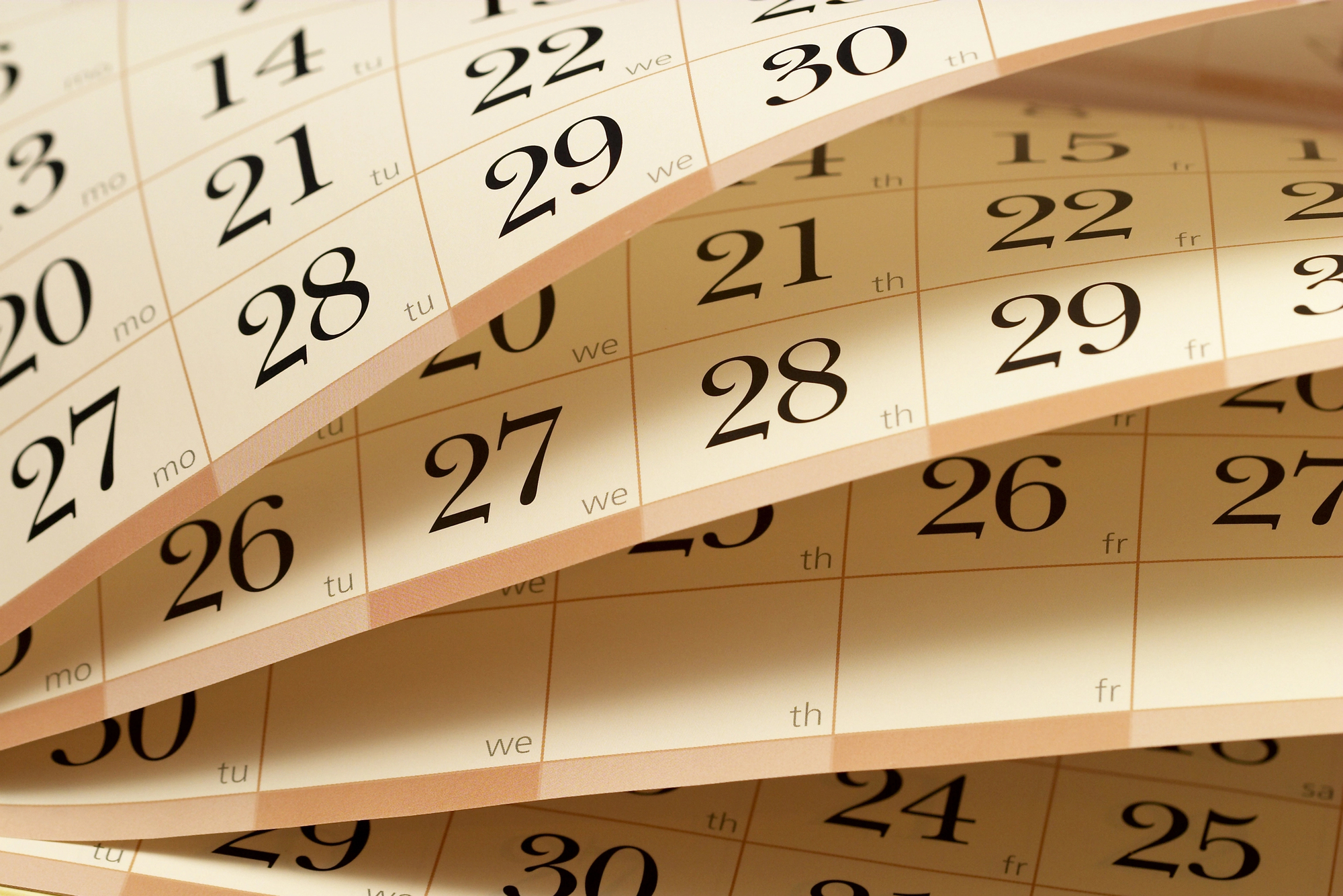 Close-up of overlapping calendar pages showing bold dates like 29, 30, 31 and weekday abbreviations (mo, tu, we, th, fr).