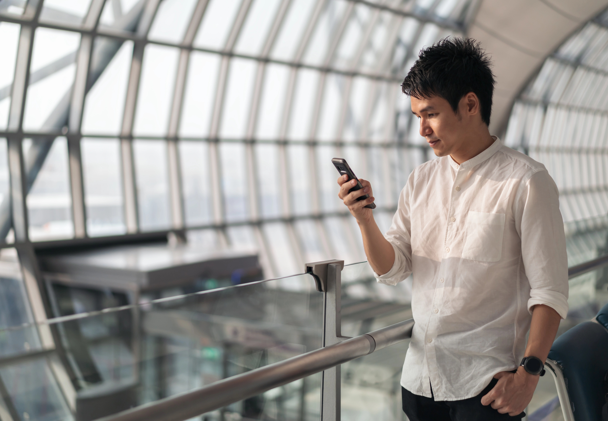 Person looking at their phone with a concerned expression at an airport departure gate, luggage nearby