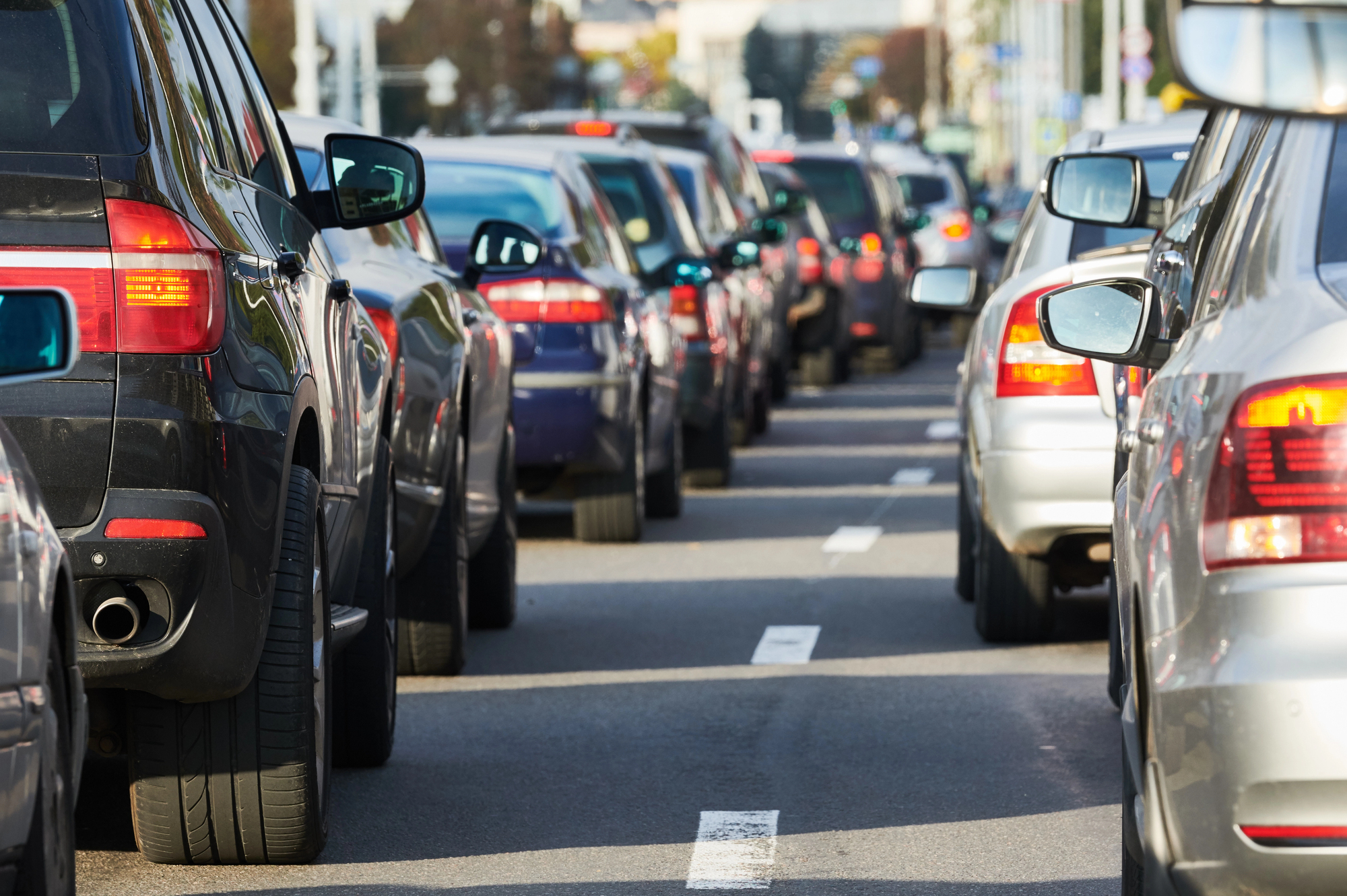 Traffic jam with rows of cars bumper to bumper on a city street, viewed from behind.”] ,