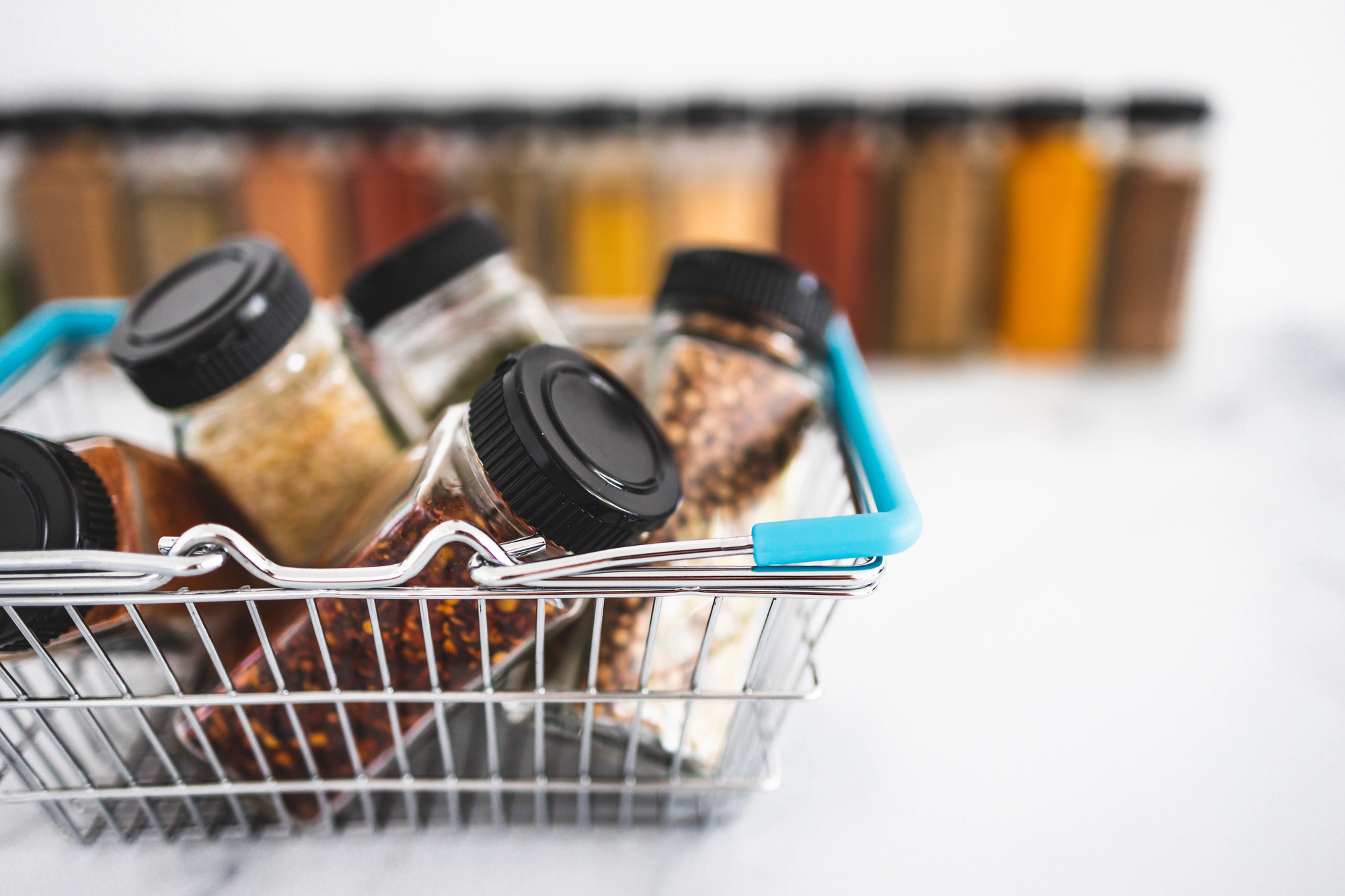 Glass spice jars can be repurposed to store small hardware, office supplies, and craft materials on a shelf
