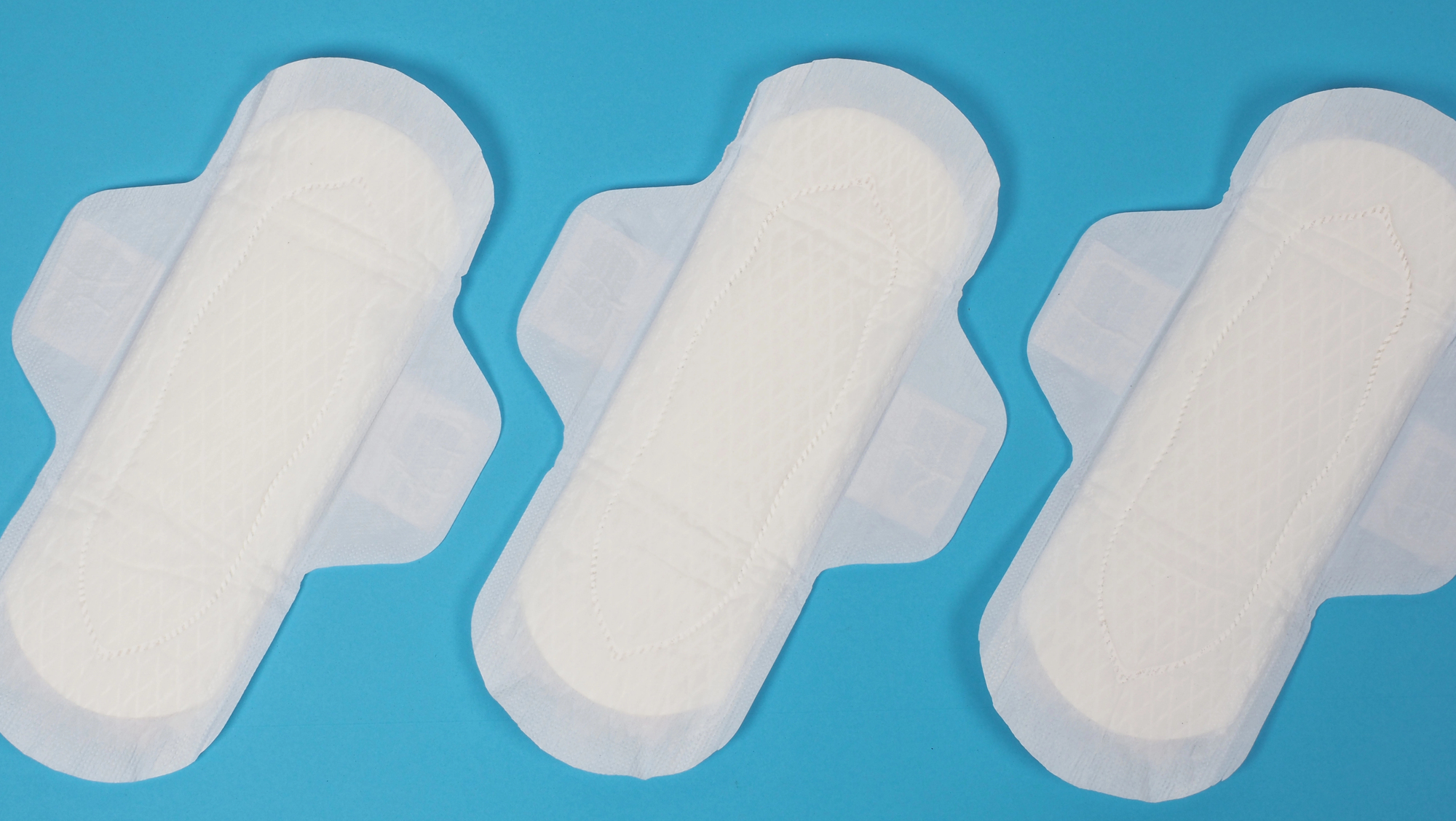 Several white sanitary pads arranged diagonally on a bright blue background.