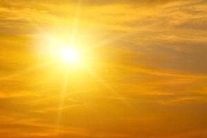 Bright sun in a golden orange sky with wispy clouds spreading warm light.