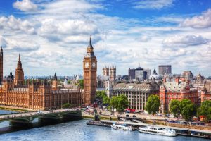 London skyline with Big Ben and the Houses of Parliament along the River Thames, Westminster Bridge nearby and boats on the water.