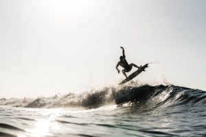 A silhouetted surfing airing on a wave breaking on a beach in puerto rico