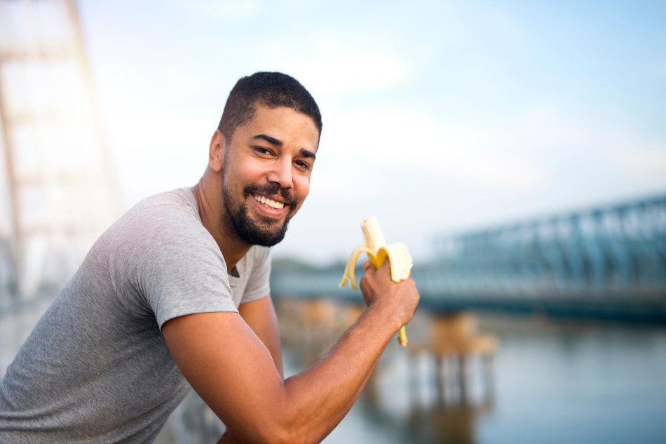 Young fit sporty person eating banana and smiling. Active lifestyle and healthy eating.