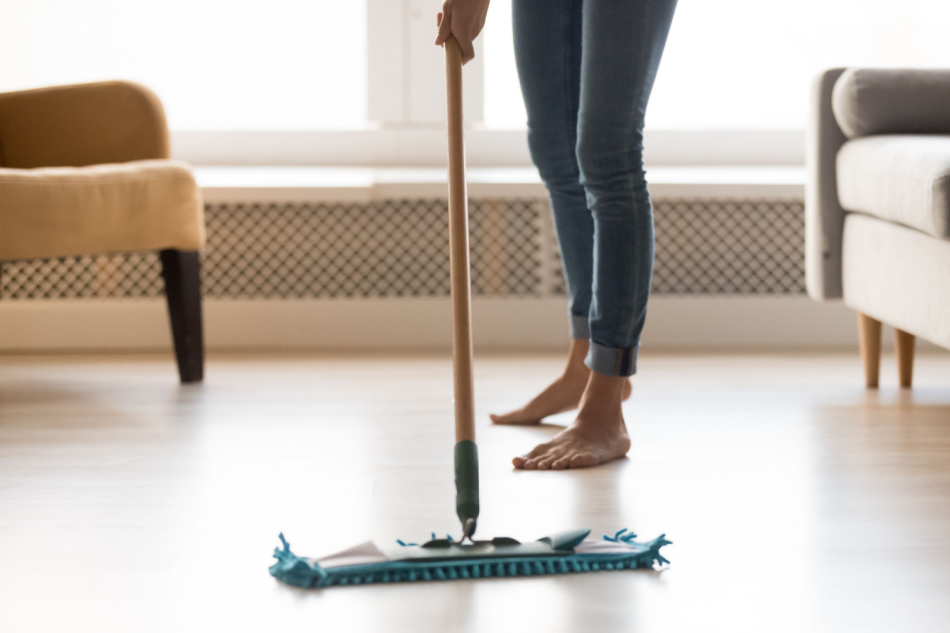 Close up cropped image of barefoot woman in casual clothes make house chores cleaning