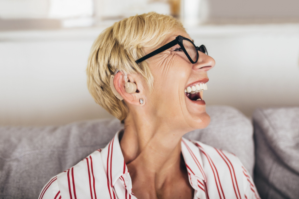 Mature woman with hearing aid indoors smiling