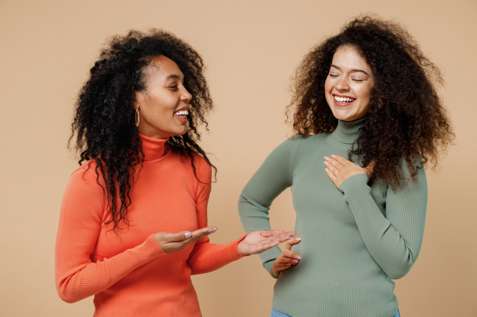 Two vivid laughing young curly haired women in casual clothes chatting