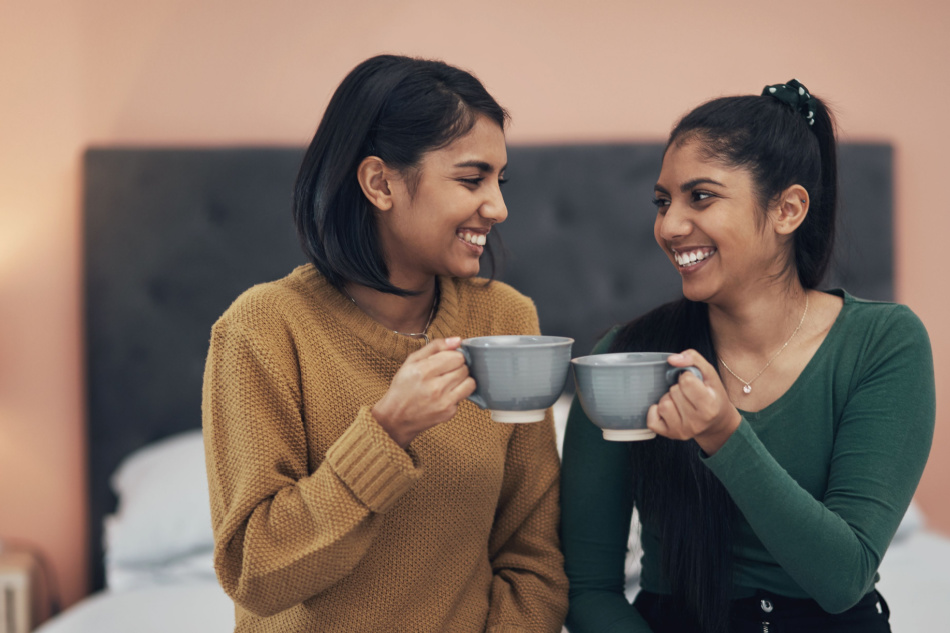 Shot of two young women drinking coffee while sitting together at home.