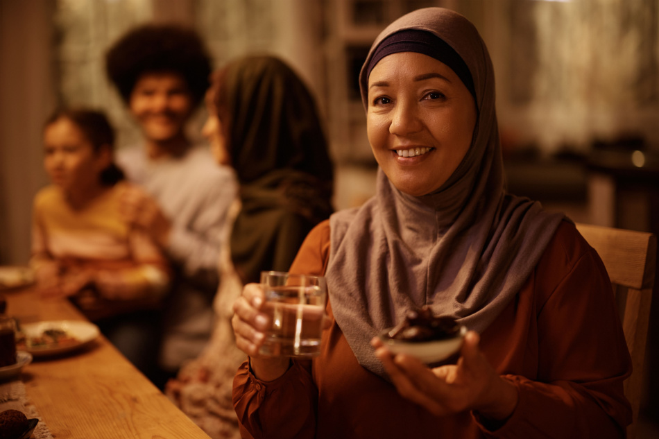 Happy mature Middle Eastern woman celebrating Ramadan with her family and looking at camera.