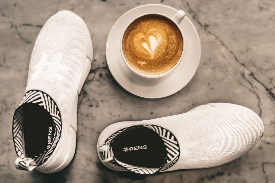 A pair of Rens sneakers next to a cup of coffee