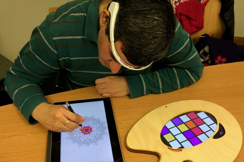 A user colors a digital mandala using a stylus on the main display. An EEG headset monitors brain signals and a peripheral display, in the form of an artists' palette, generates new colors based on the EEG data.