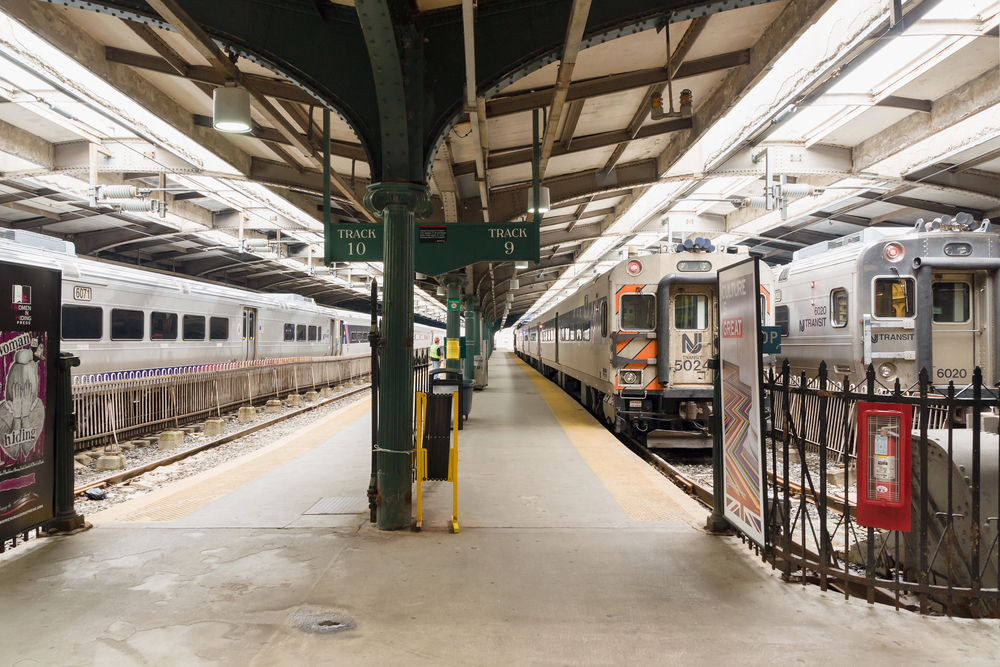 Train platform with trains on both sides, a green central pillar, and signs for Track 10 and Track 9.