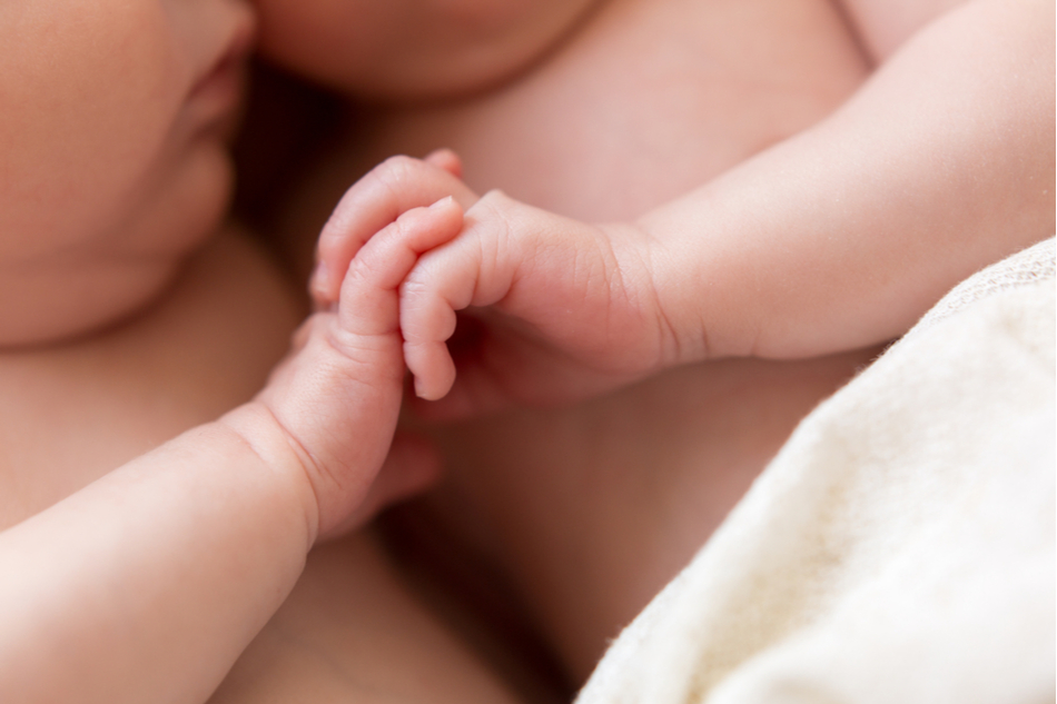 Close up of newborn baby twins holding hands