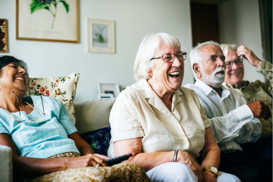 Elderly people sitting and laughing on a couch at home
