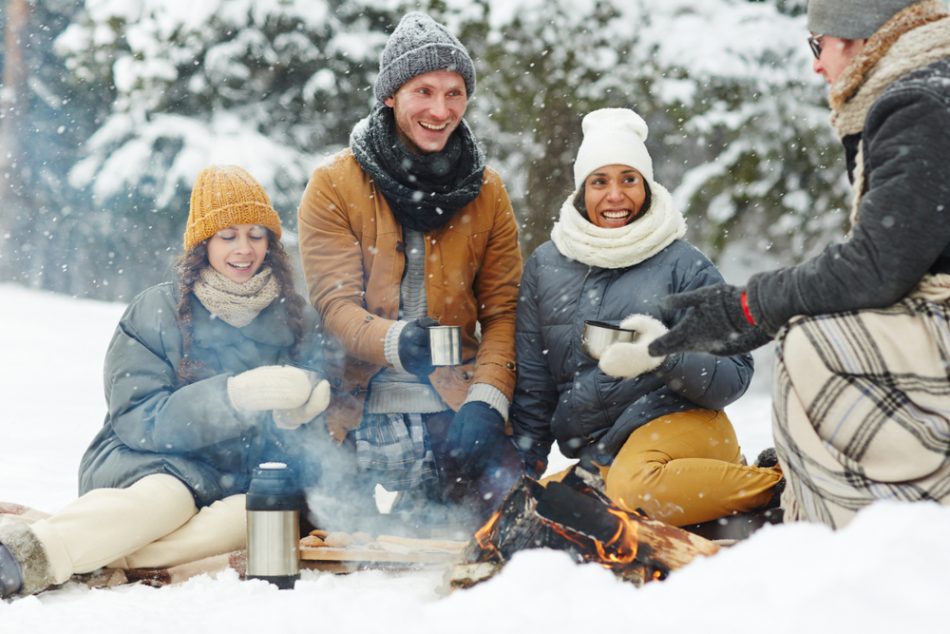 a diverse group of four friends enjoy an outdoor social gathering in the winter