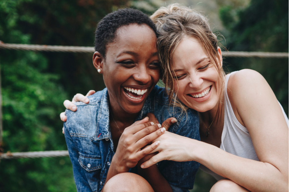two diverse female friends hug and laugh