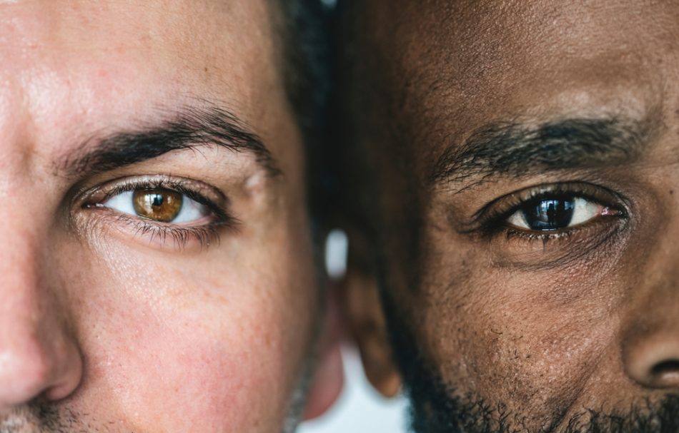 close up of one white man's eye and one black man's eye