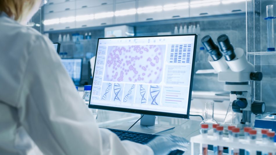Female scientist in a white lab coat inspecting cancer cells and their DNA in laboratory.
