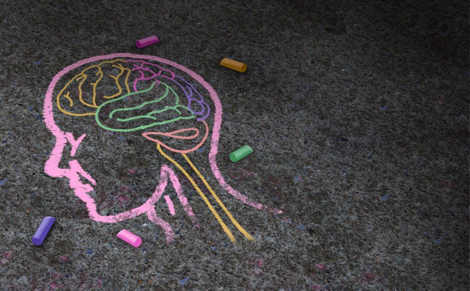 Chalk drawing of a brain on asphalt in different colors.