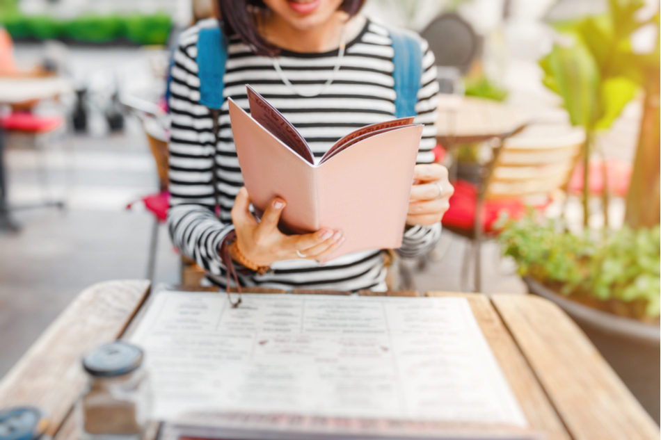 woman in striped shirt looks through menu at a restaurant