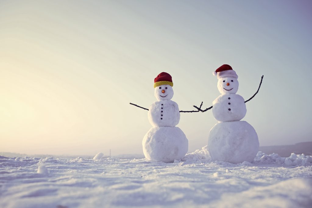two snowmen hold hands in a snowy field