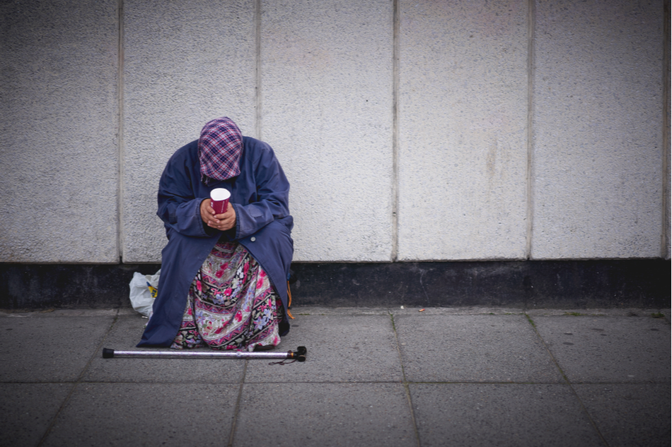 homeless woman begs on a street in London, UK