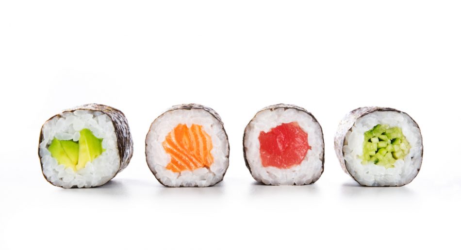 Four maki rolls in a row with salmon, avocado, tuna and cucumber isolated on white background.