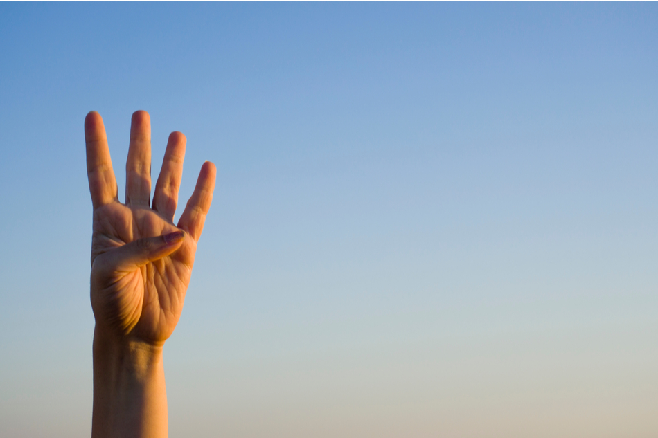 White person's hand showing four fingers with blue sky background