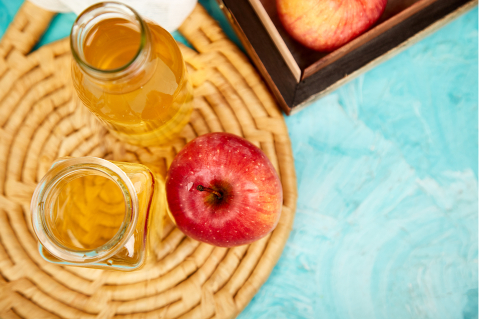 Apple cider vinegar on table next to apple