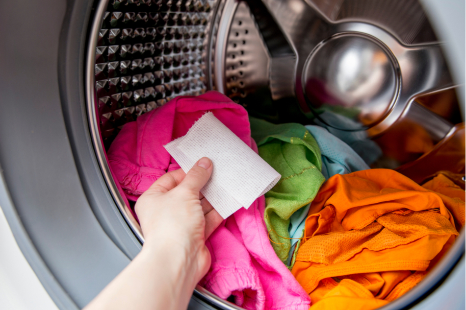 person putting dissolvable laundry sheets in washing machine