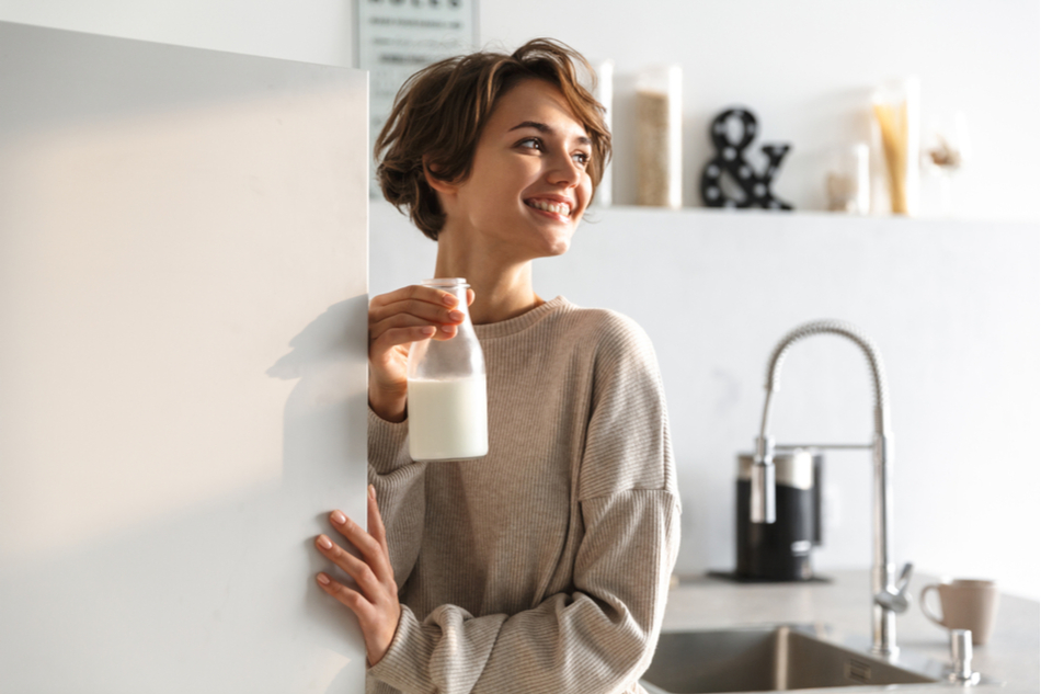 woman gets bottle of milk out of fridge