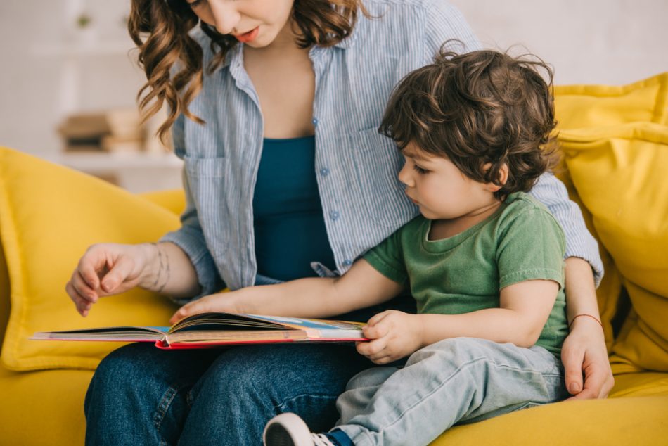 Mother and son reading a book on a yellow couch