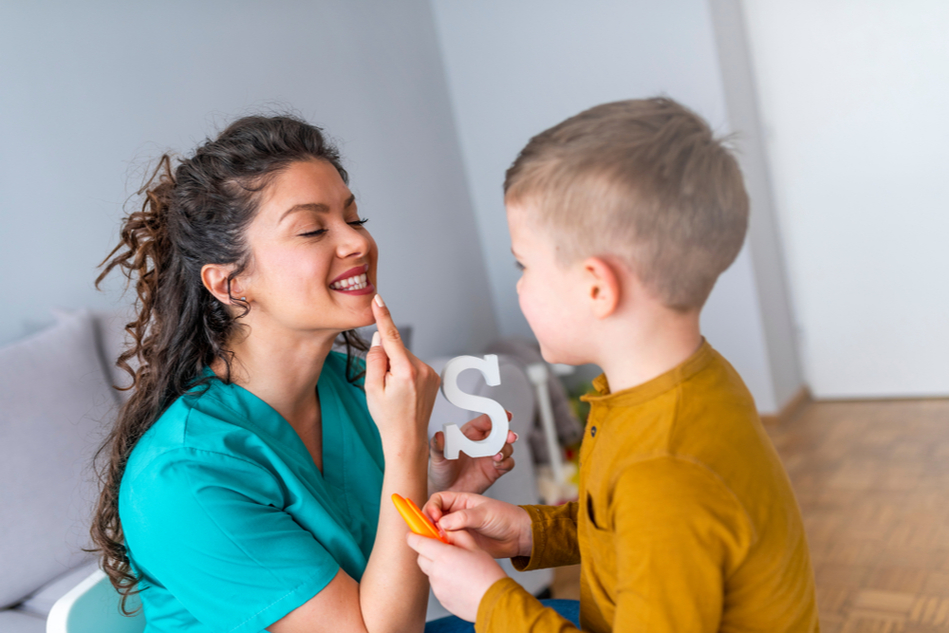 Woman speech therapist doing speech exercises with with stuttering boy