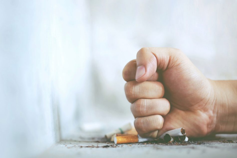 Hand in a fist destroying cigarettes.