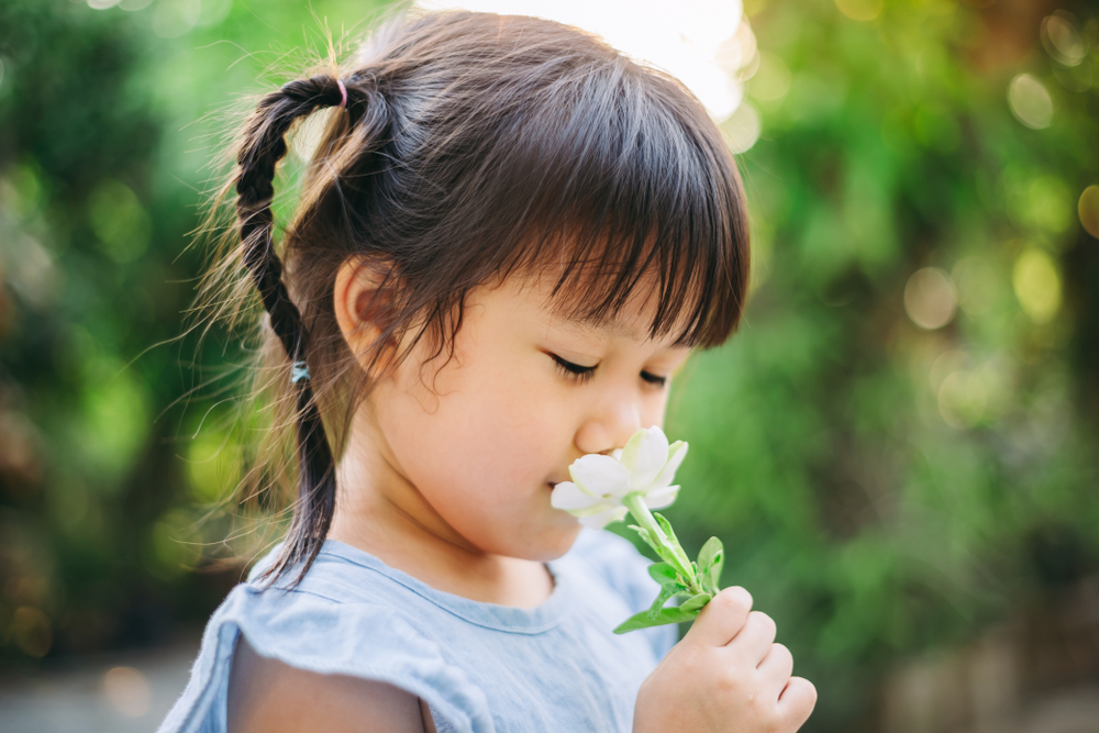 Young girl smelling a white flower