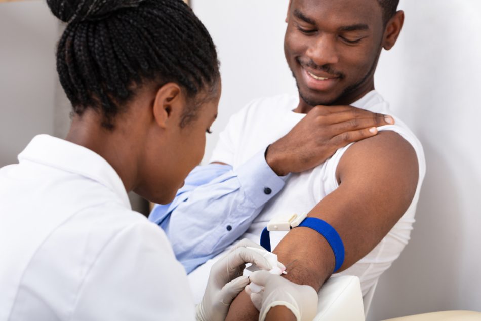 Doctor performing blood test on smiling patient
