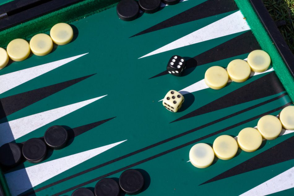 Backgammon game in starting position seen diagonally with a black six and a white five on the dice as a classic start.