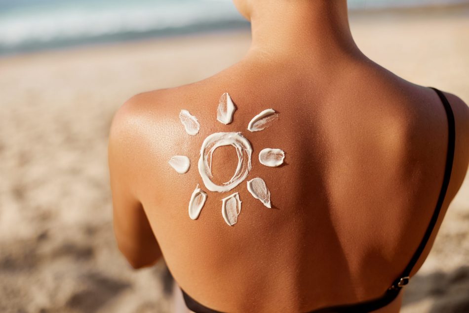 view of woman's back with sunscreen applied on her shoulder in the shape of a sun