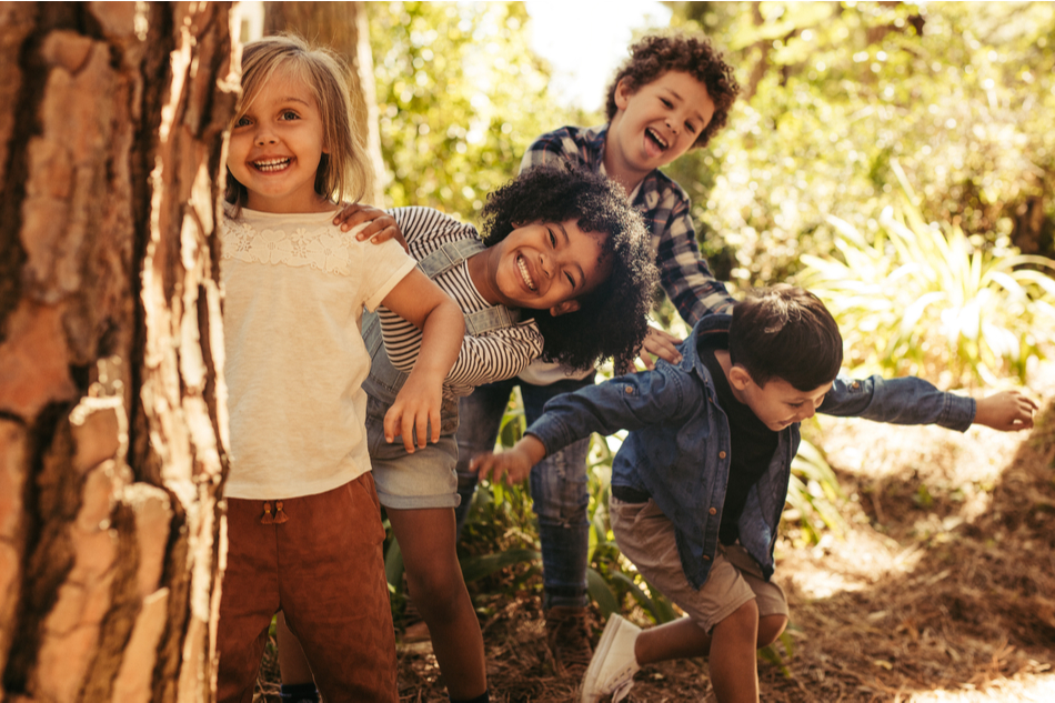 four diverse children play and learn in the forest