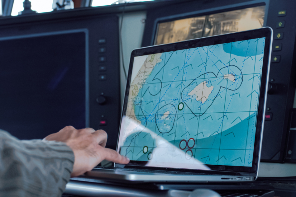 Captain of Commercial Fishing Ship Working with Sea Maps Surrounded by Monitors and Screens