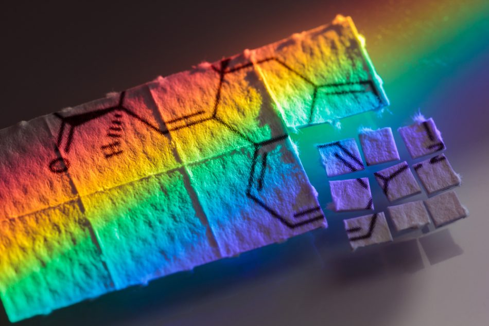 Pieces of rainbow colored paper with chemical structure of LSD on, micro dosing concept.