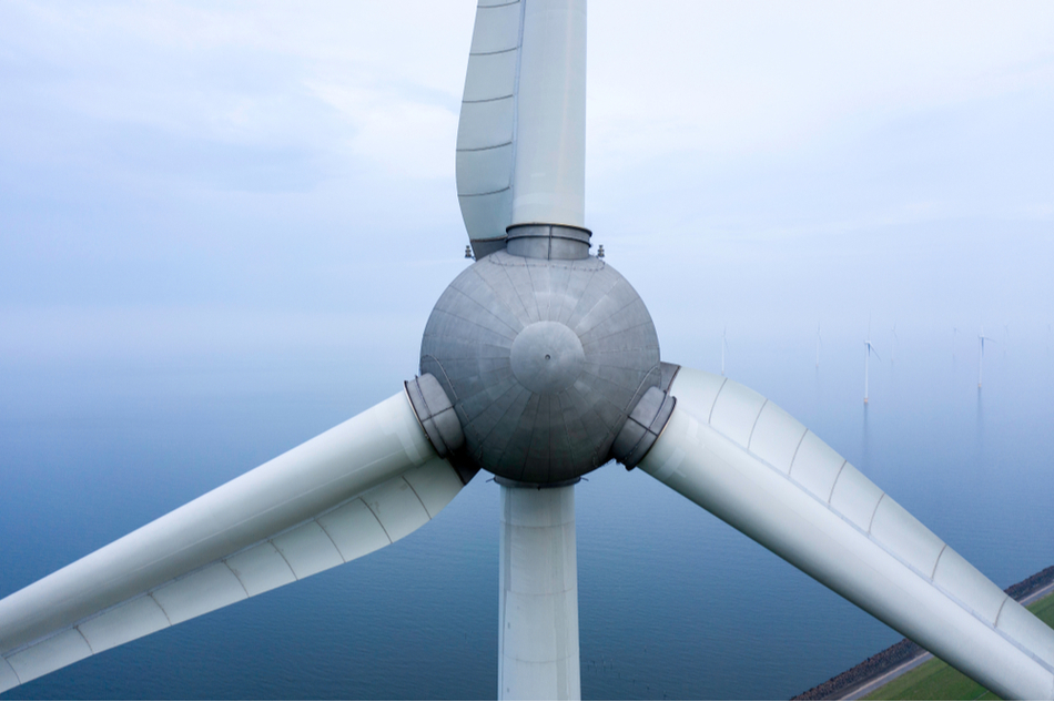 Close-up view of a wind turbine with the ocean in the background