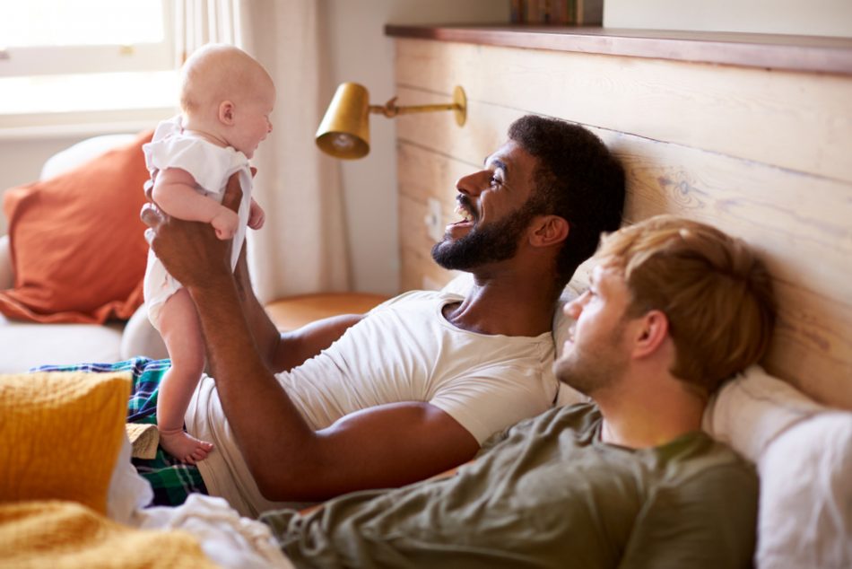 Same-sex couple in bedroom with their child.