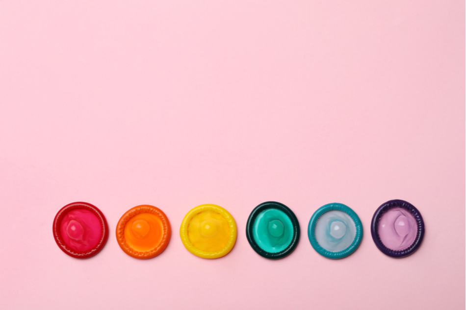colorful condoms against pink backdrop